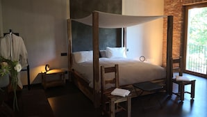 Un letto a baldacchino con tenda, un tavolino, due sedie e una pianta in vaso.