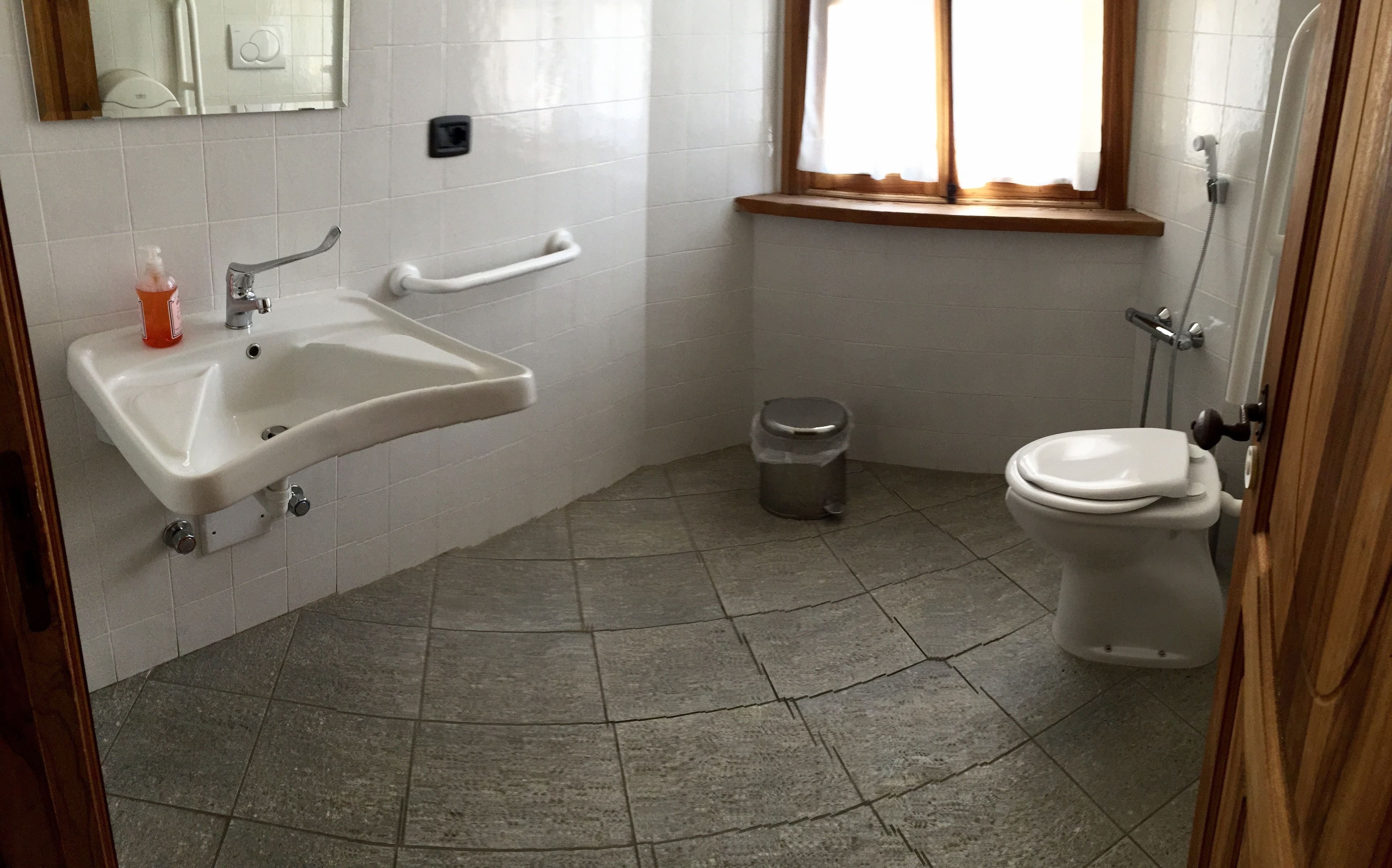 A bathroom with a sink, toilet, and trash can.