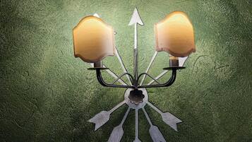 A wall-mounted light fixture with a central bulb and two lamps on either side, connected by metal arms.