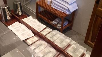 A bathroom with a glass sink, a wooden shelf with toiletries, and a mirror.