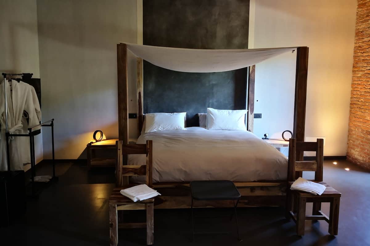 A bedroom with a four-poster bed, wooden furniture, and a robe rack.