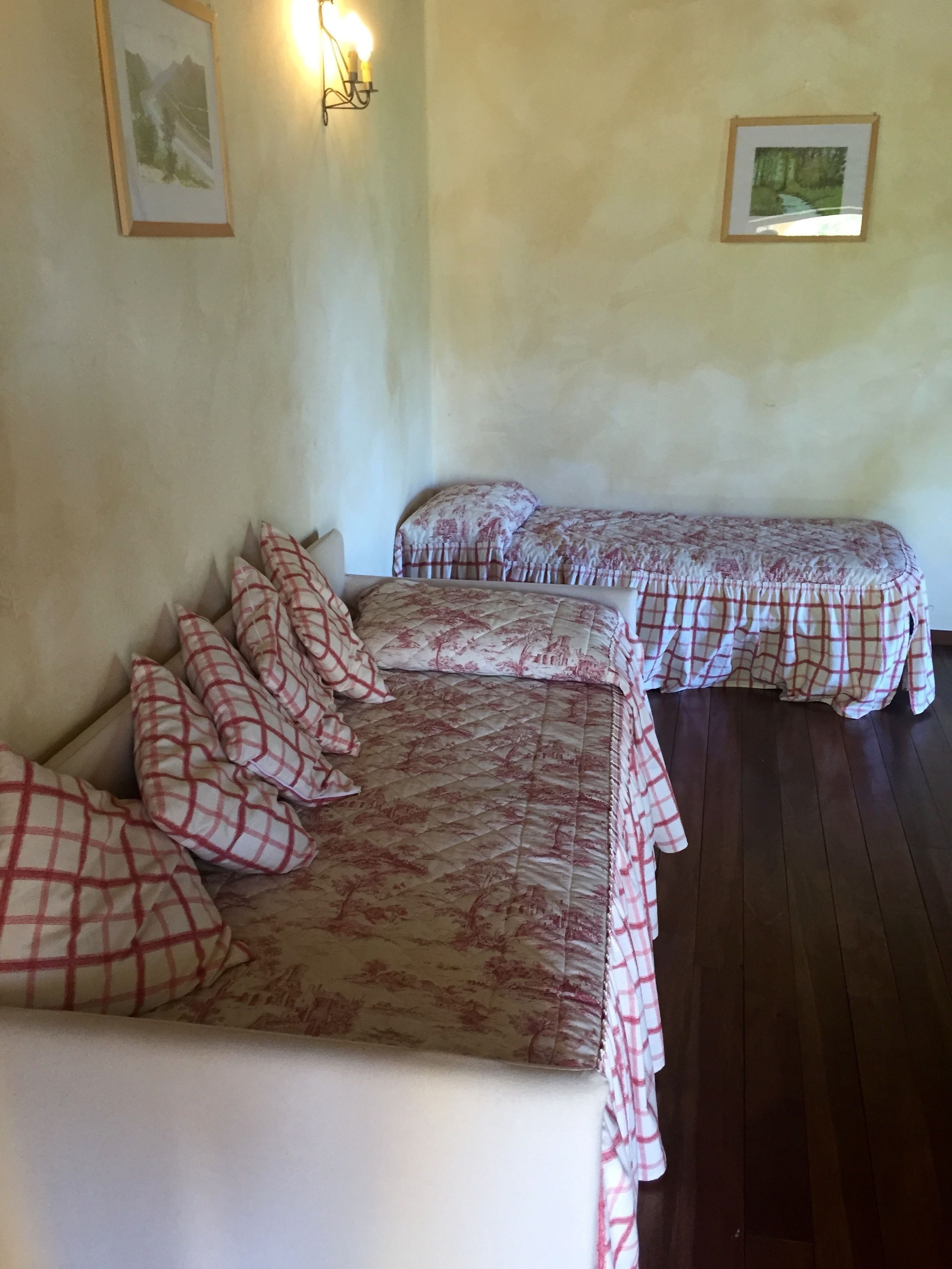 Una habitación con dos camas, cada una con una colcha de estampado floral y almohadas a juego. Hay dos cuadros en las paredes, uno sobre cada cama.