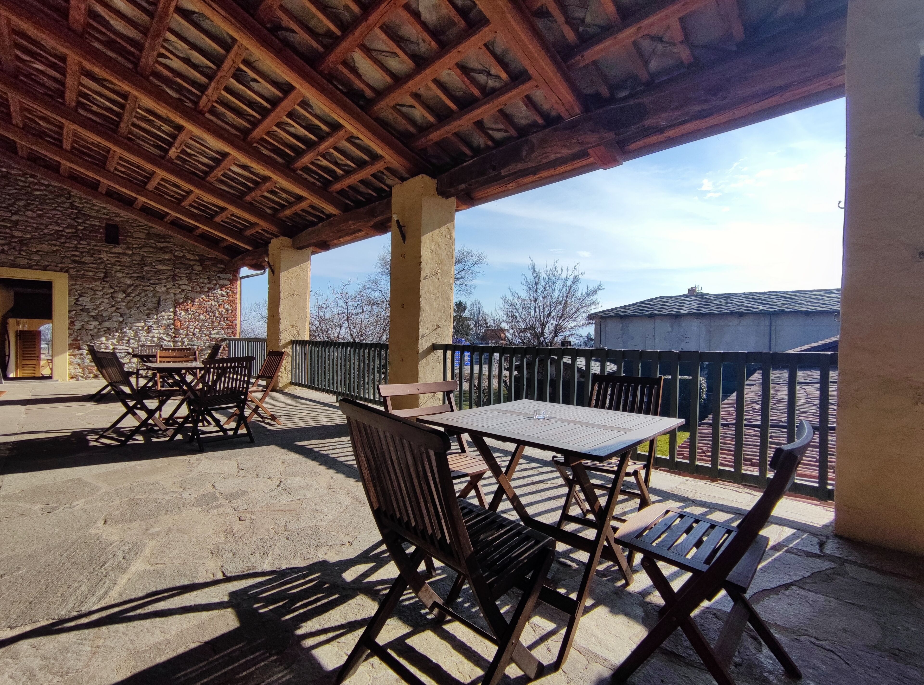 Une terrasse extérieure avec des murs en pierre, des meubles en bois et une vue sur les environs.