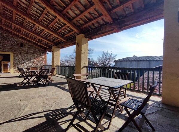 An outdoor patio with stone walls, wooden furniture, and a view of the surrounding area.