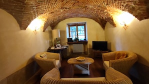 Una stanza accogliente con soffitto in mattoni, due divani in vimini, un tavolino, una televisione e una finestra con piante.