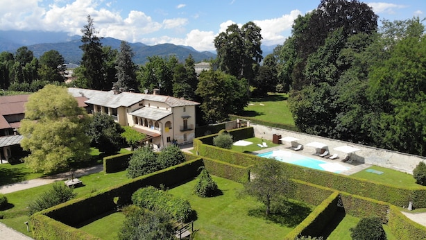 Una grande proprietà con piscina, giardini curati e un edificio con diversi balconi.