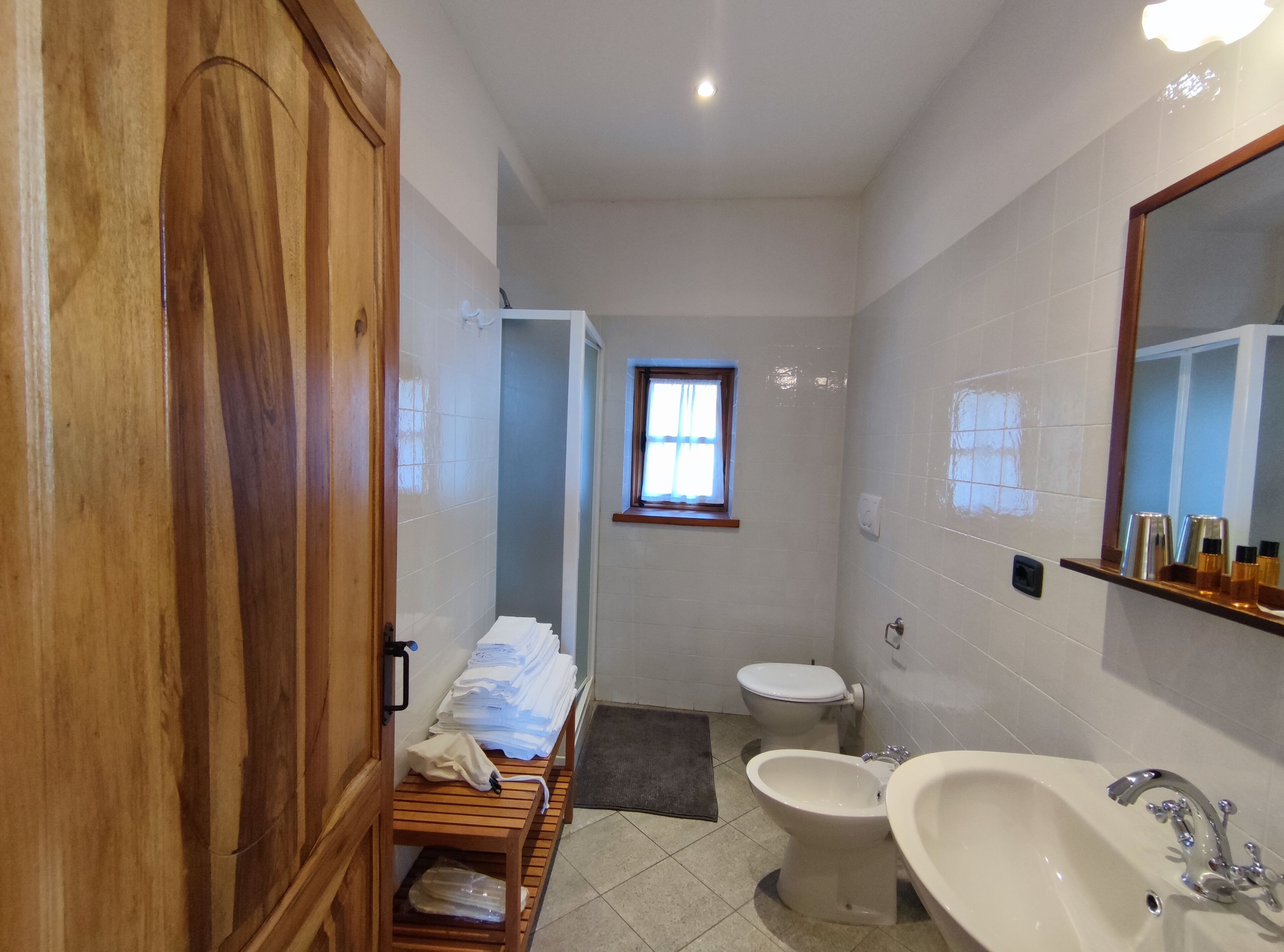 Un baño pequeño con un armario de madera, un inodoro, un bidé y un lavamanos.