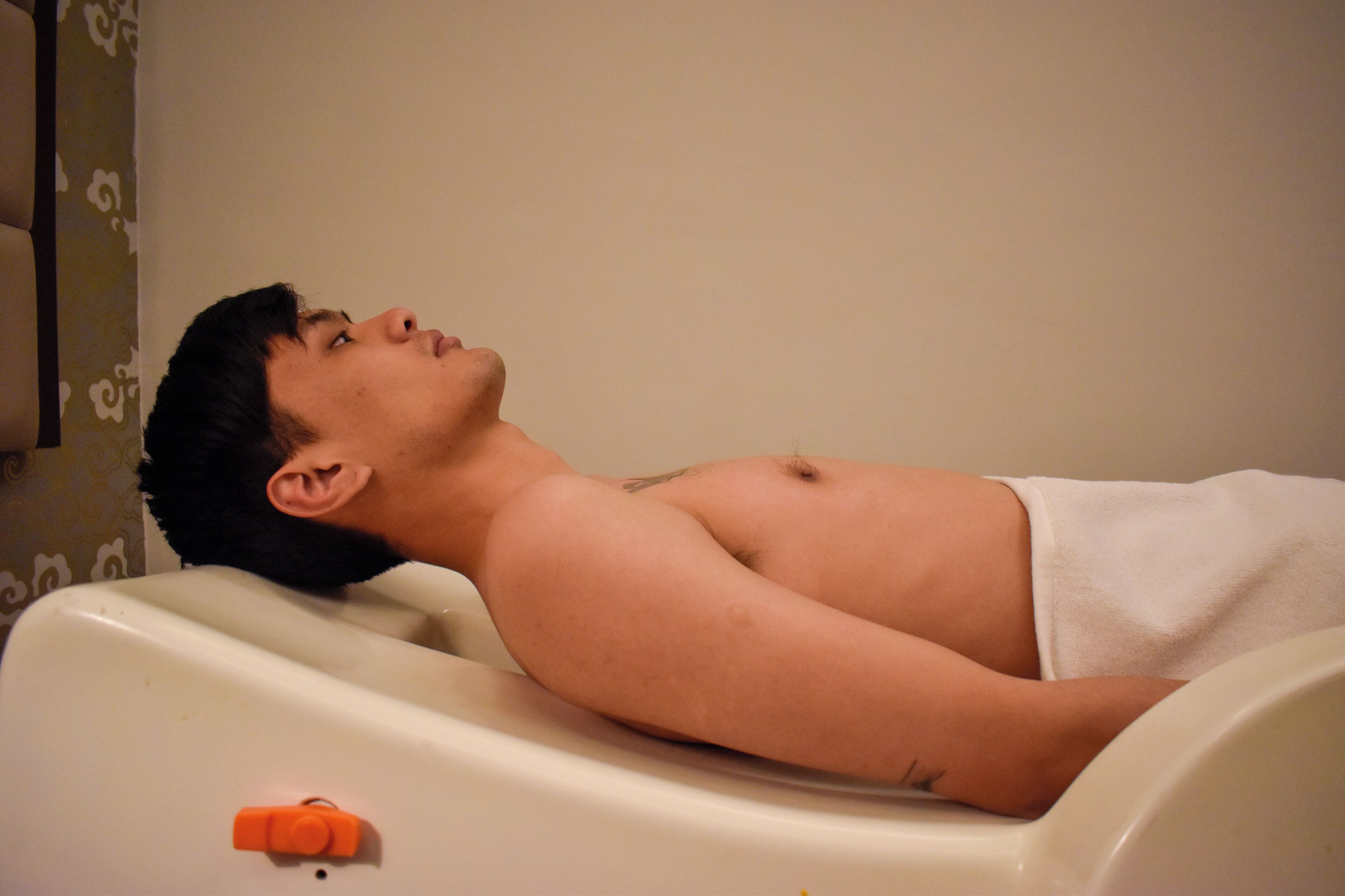 Una persona recostada en una bañera con una toalla alrededor de la cintura.