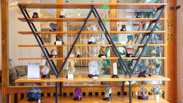 Una exhibición de diversos minerales y rocas sobre estantes y mesas de madera.
