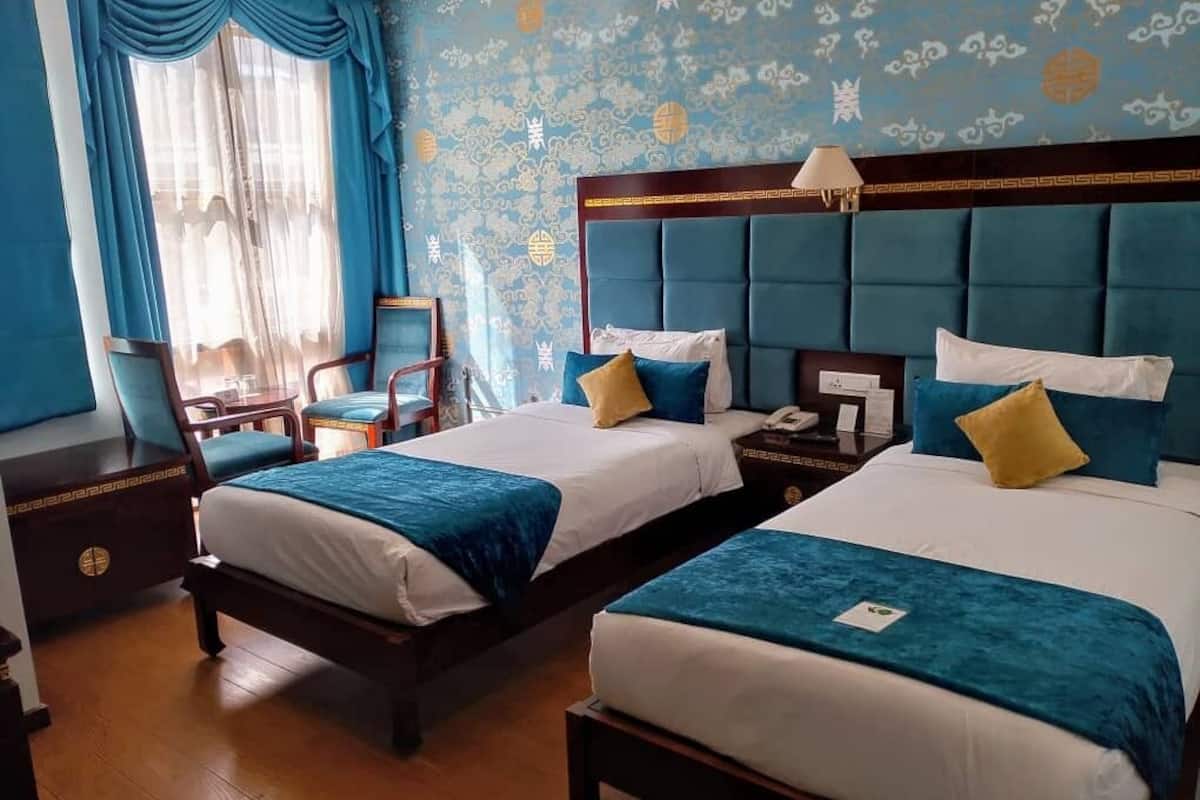 Une chambre d’hôtel avec deux lits, une table de chevet, une chaise et un bureau.