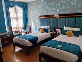 Una habitación de hotel con dos camas, una mesita de noche, una silla y un escritorio.