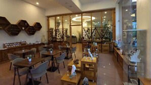 Un restaurante con mesas y sillas de madera, un expositor de vidrio y una escalera que lleva a un nivel superior.