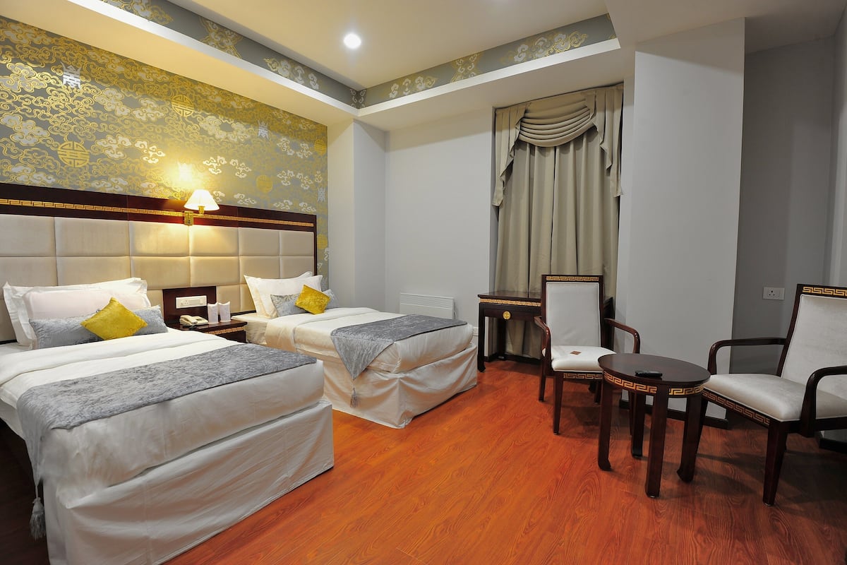Une chambre d’hôtel avec deux lits, un bureau, une chaise et une lampe.