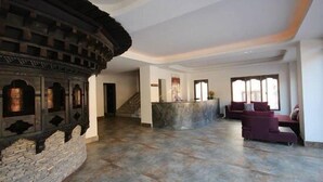 A spacious lobby with a stone wall and a curved ceiling, a reception desk, and seating area with sofas.