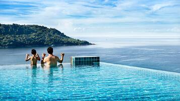 Una piscina al aire libre, sombrillas, sillones reclinables de piscina