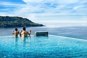 Una piscina al aire libre, sombrillas, sillones reclinables de piscina