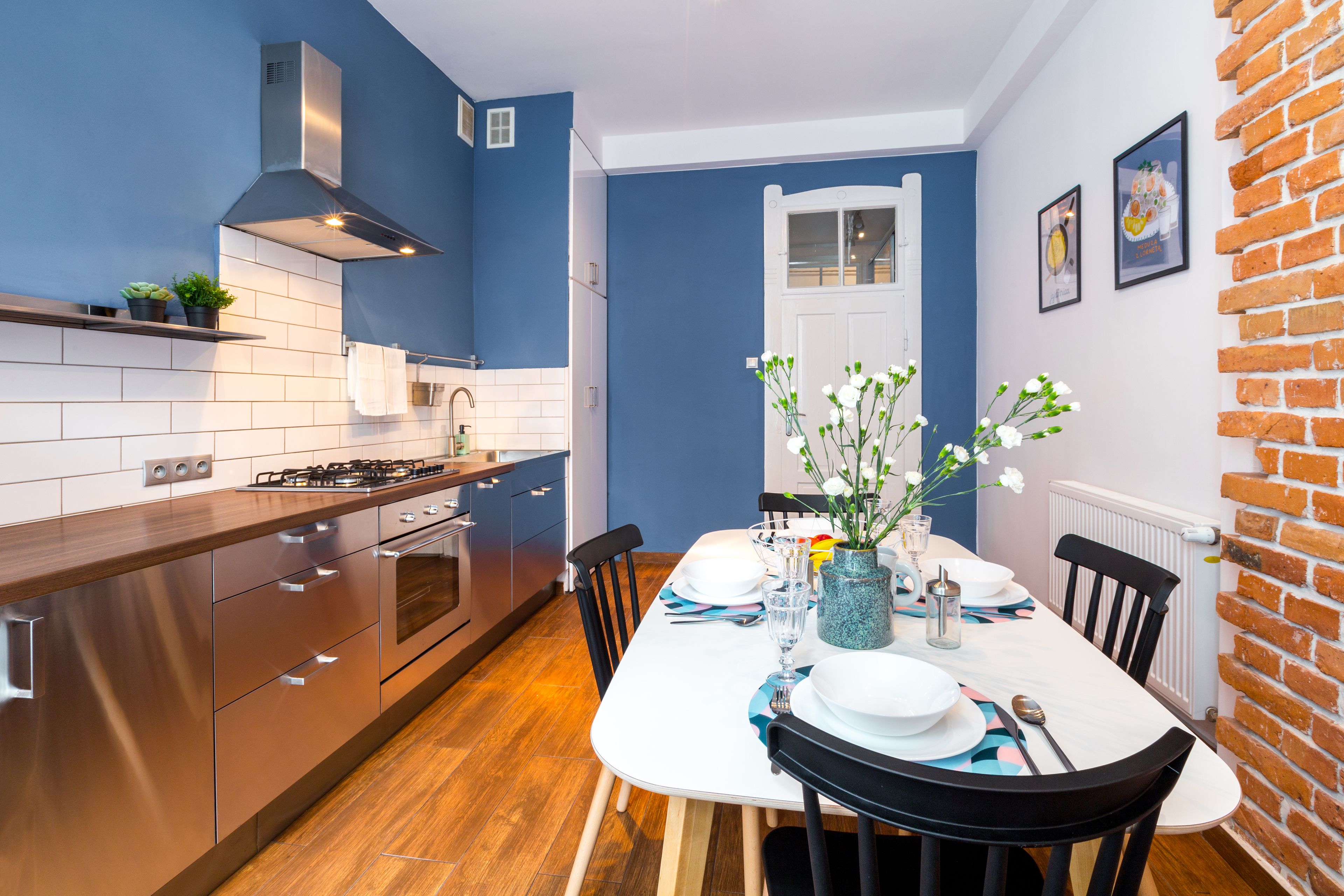 A modern kitchen with stainless steel appliances, a white tiled backsplash, and a brick accent wall.