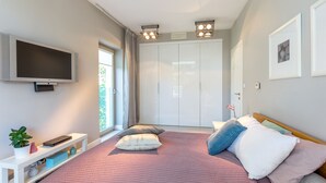 Un dormitorio con cama, televisión, armario y ventana.
