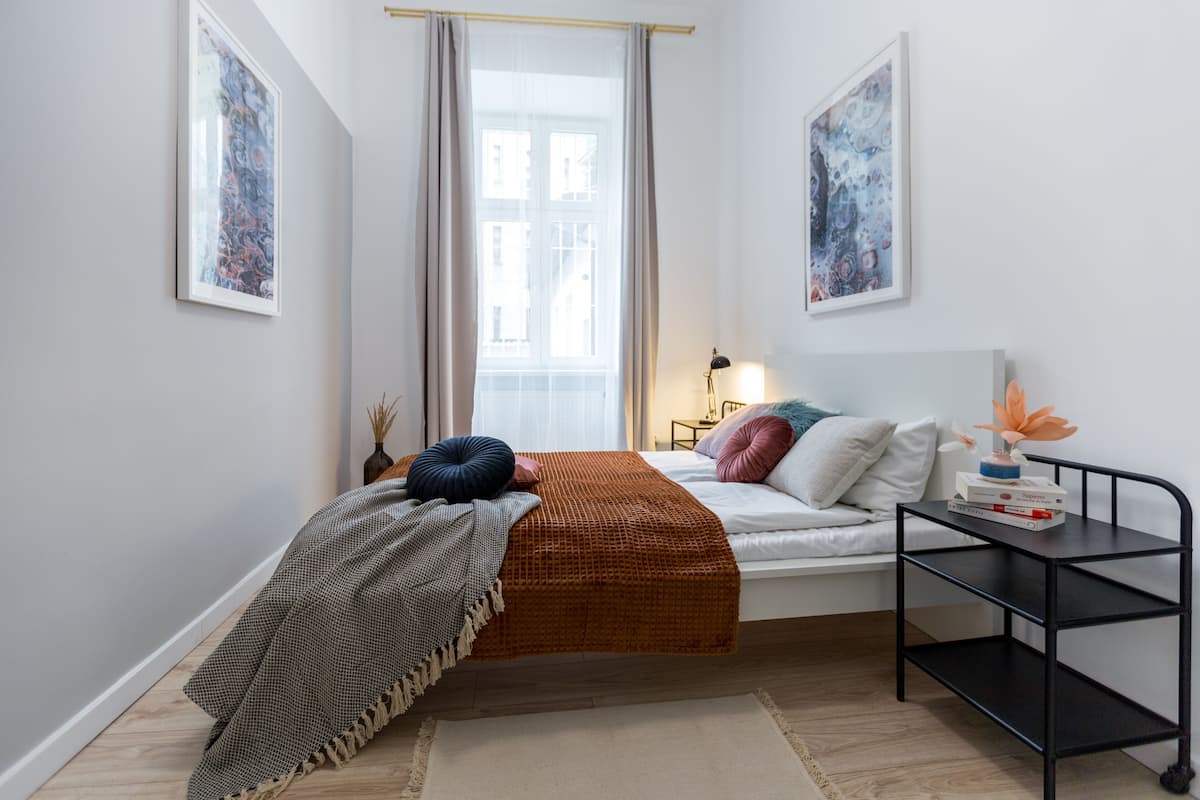A modern bedroom with a bed, bedside table, and artwork on the walls.