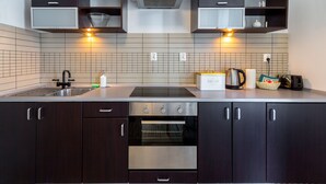 Una cocina moderna con armarios oscuros, horno de acero inoxidable, microondas integrado y un lavamanos doble.