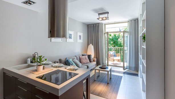 Una cocina moderna con una isla central, un comedor con sofá y vistas al exterior.