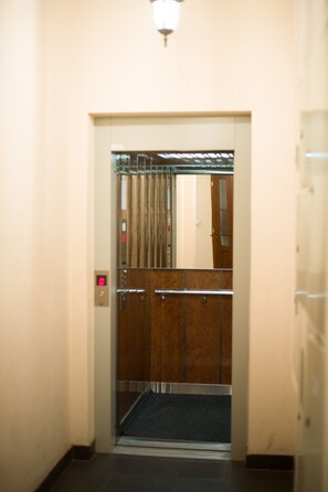 An elevator with a metallic door and a control panel with a red light.