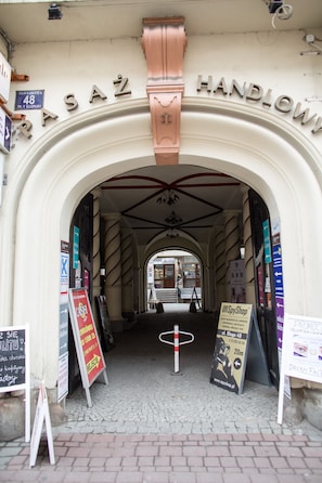 An entrance with a sign reading "Handlowi" and various advertisements.