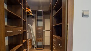A walk-in closet with wooden shelving and drawers, a ladder, and a hanging rack. - FriendHouse Apartments – Old City (Kraków)