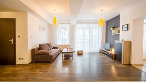 A modern living room with a brown sofa, a coffee table, and a TV stand. - FriendHouse Apartments – Old City (Kraków)