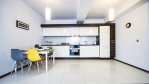 A modern kitchen with white cabinets, a dining table with chairs, and pendant lighting. - FriendHouse Apartments – Old City (Kraków)