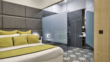 A modern bedroom with a large bed, a glass-enclosed shower, and patterned flooring.