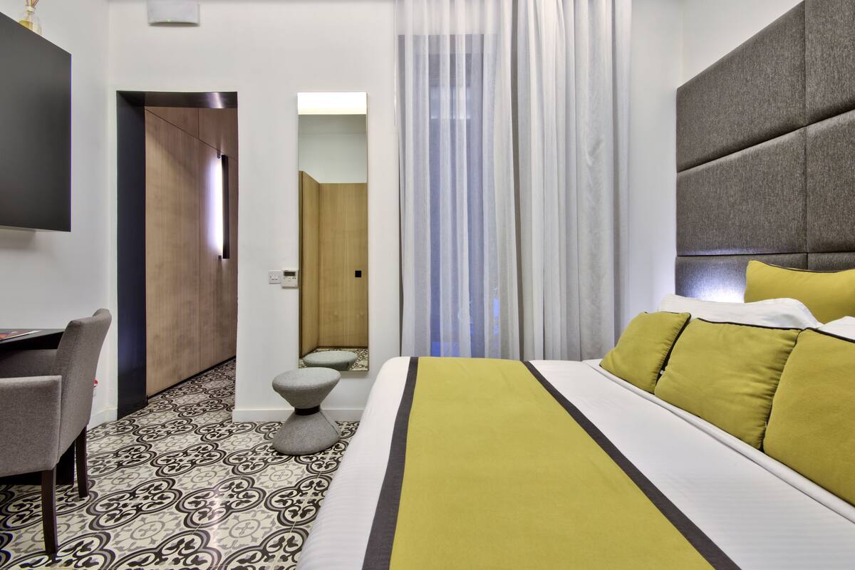 Una habitación de hotel con cama, escritorio y espejo.