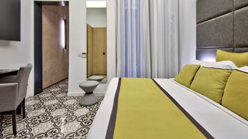 A hotel room with a bed, a desk, and a mirror.