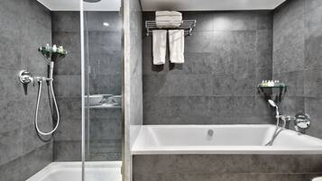 A modern bathroom with a glass-enclosed shower, a freestanding bathtub, and a towel rack with folded towels.