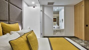 A hotel room with a bed, a bathroom with a mirror, and a wardrobe.