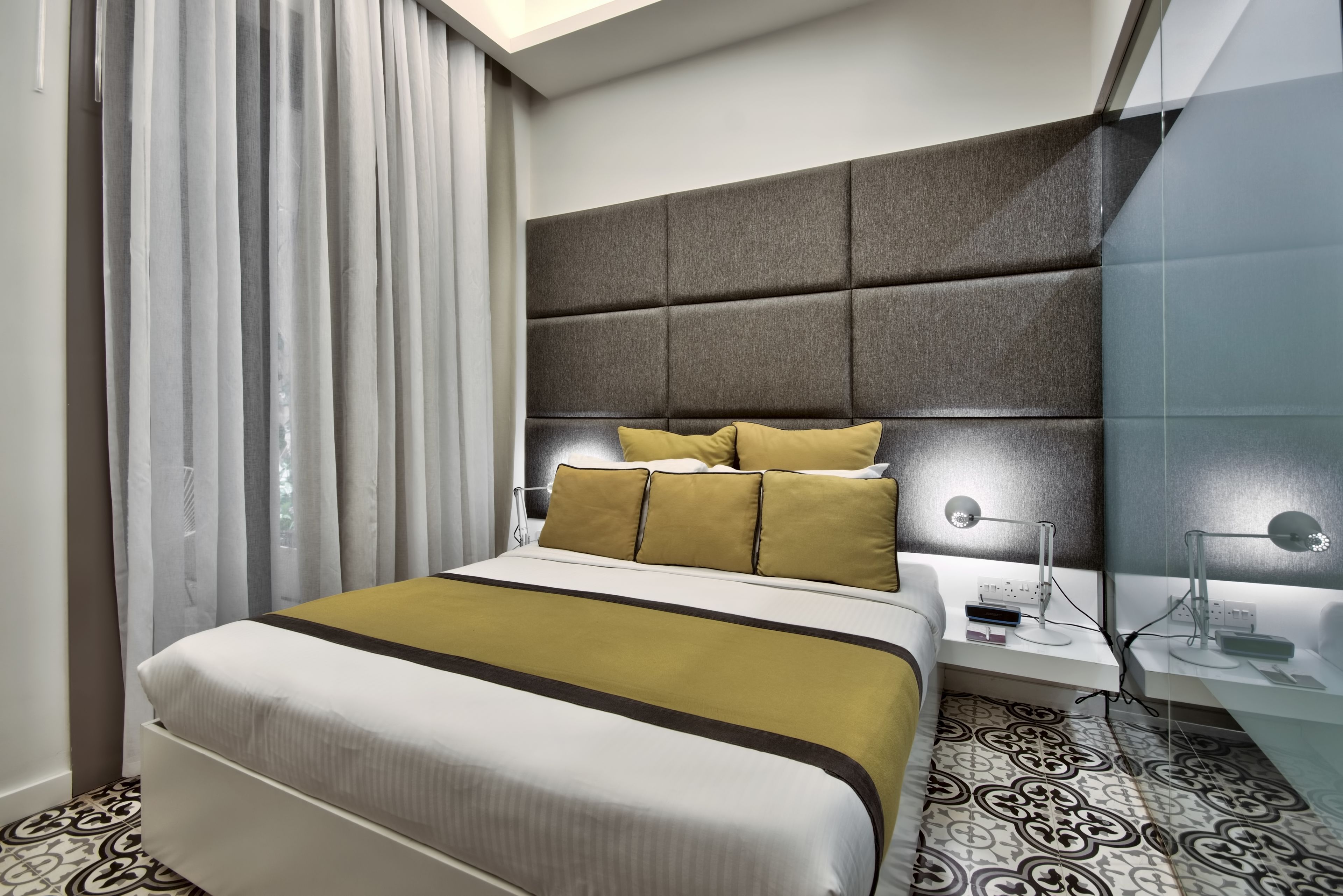 Een moderne hotelkamer met een groot bed, een nachtkastje met lamp en een kamer met een patroon.