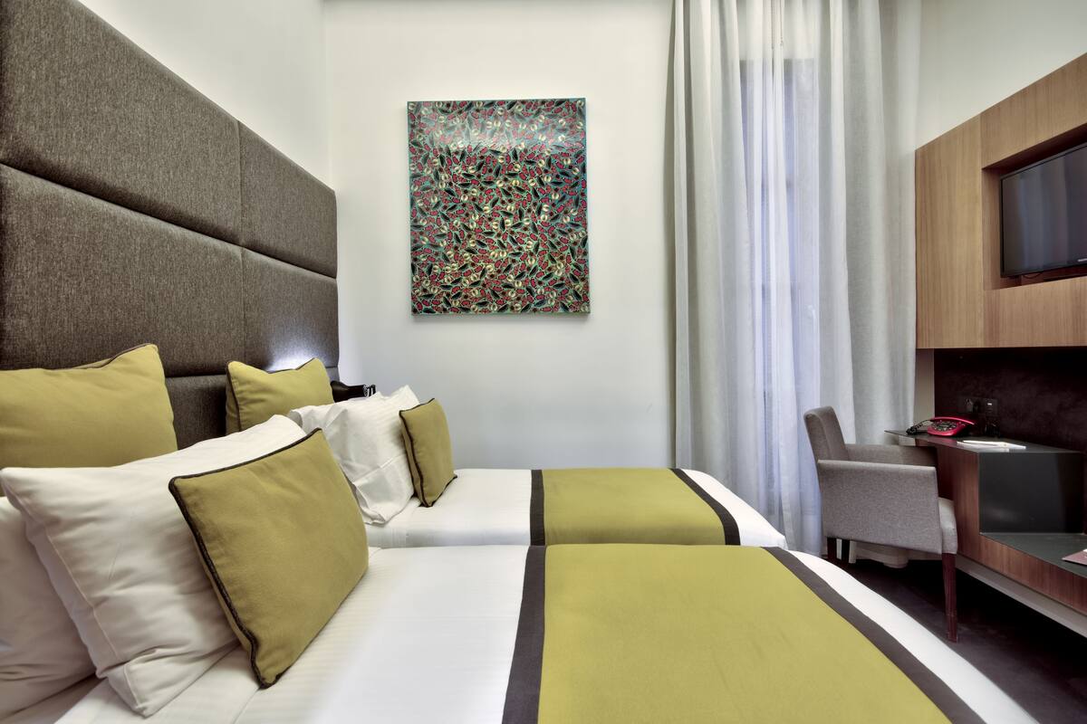 Una habitación de hotel con una cama grande, un escritorio, una silla y un televisor.