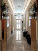 Um hall de hotel com piso de mármore, balcão de recepção e plantas em vasos.
