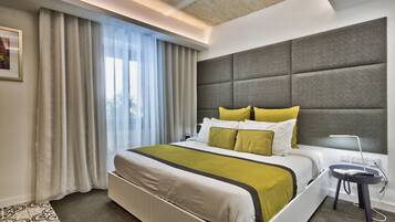 A modern hotel room with a large bed, grey headboard, and a bedside table with a lamp.