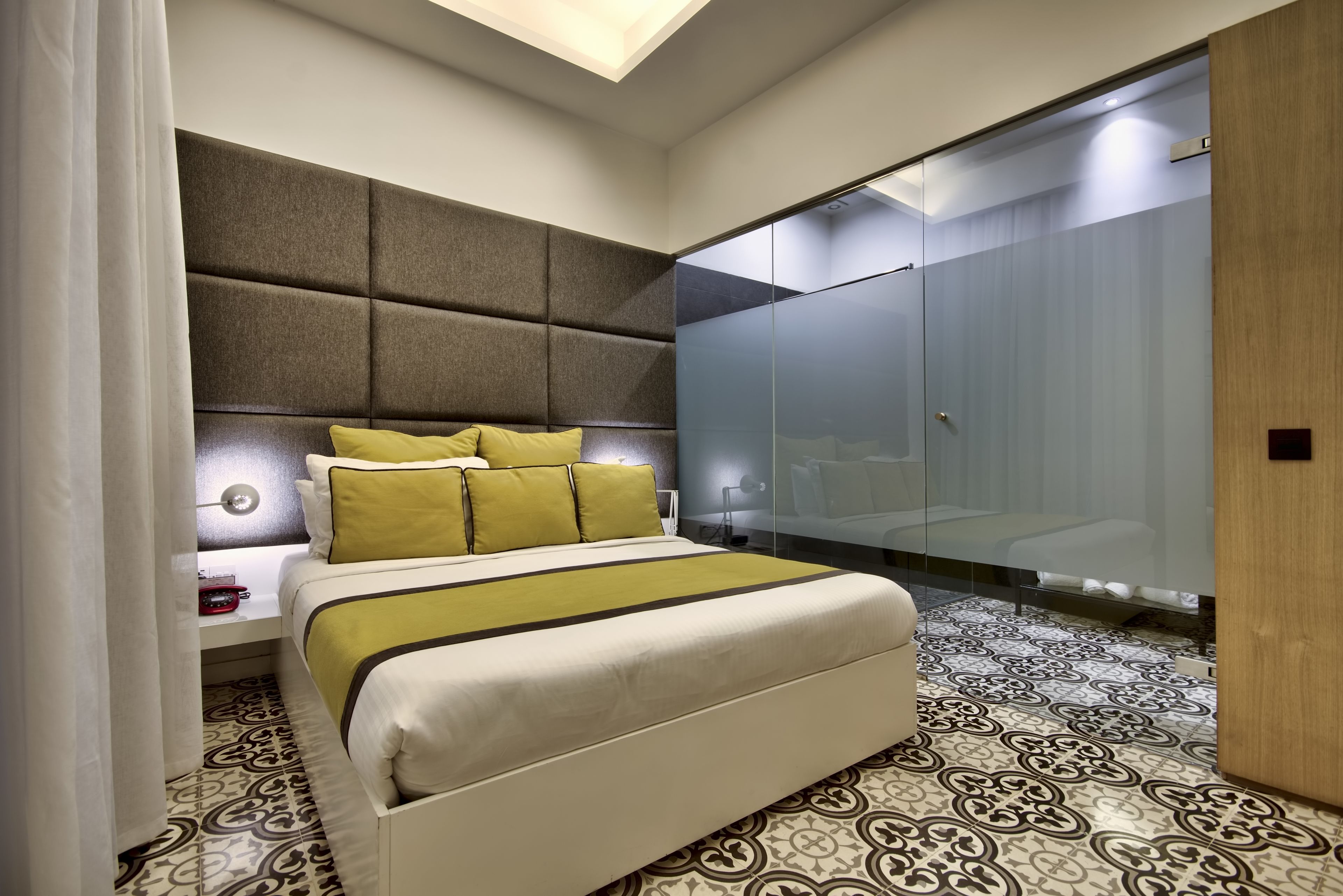 Un dormitorio moderno con una cama grande, cabecero, armario y suelo estampado.