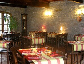 Ein Restaurant mit mehreren Tischen, Holzstühlen und einer Steinwand.