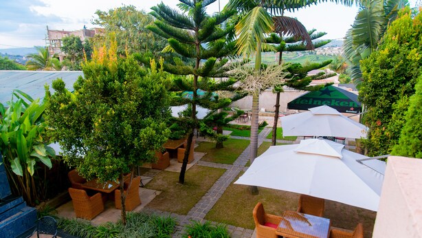 A patio area with outdoor seating, a view of the city, and a large umbrella. - Legend Hotel (Kigali)