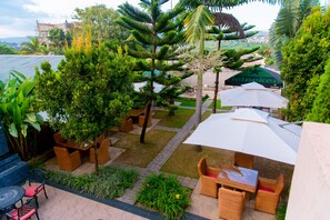 A patio area with outdoor seating, a view of the city, and a large umbrella. - Legend Hotel (Kigali)