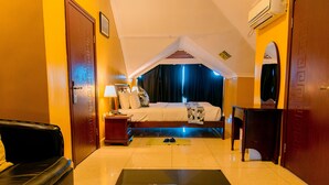 A hotel room with a bed, a desk, a chair, a couch, and a small table. - Legend Hotel (Kigali)