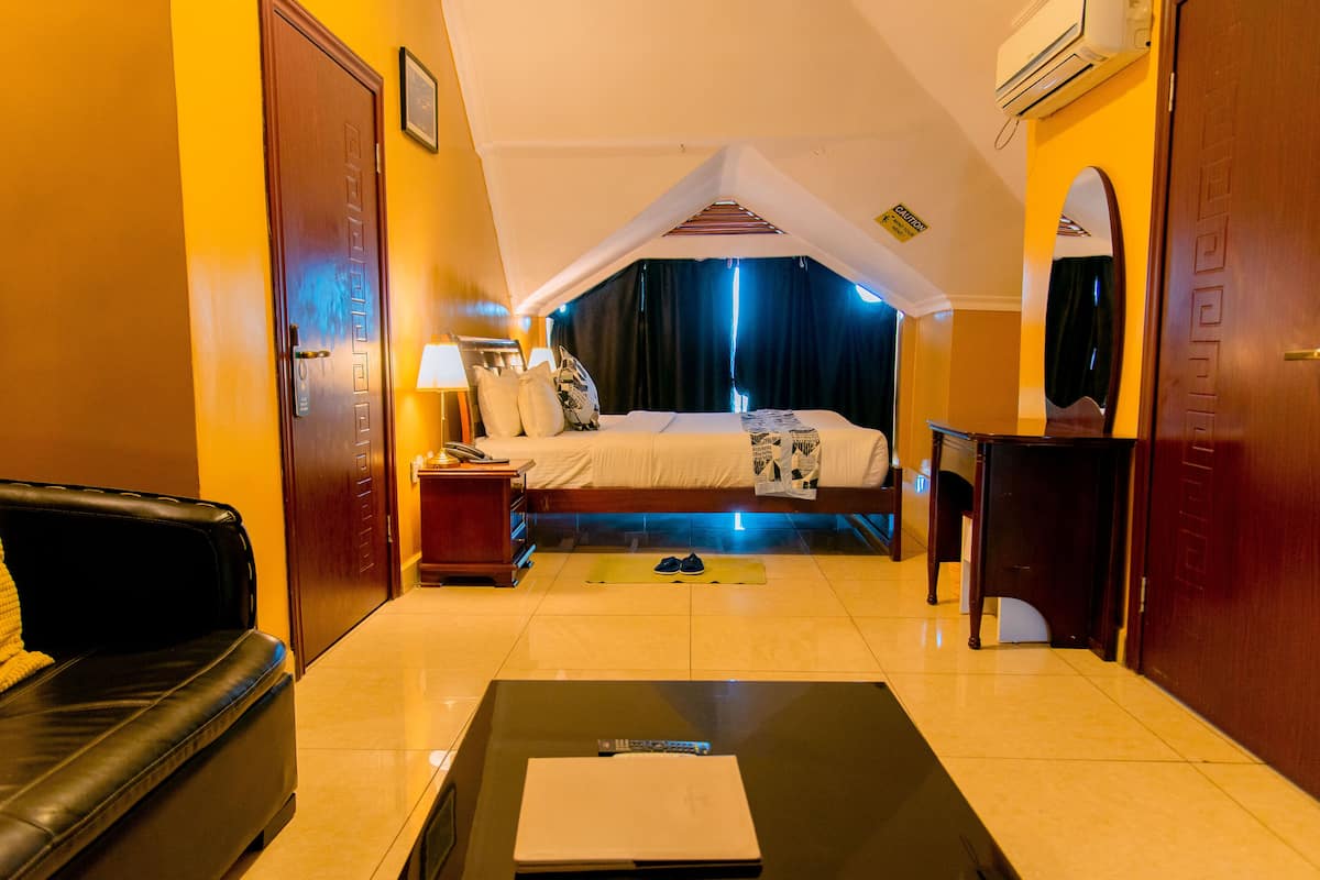 A hotel room with a bed, a desk, a chair, a couch, and a small table.