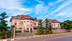 A large, two-story house with a curved roof, multiple balconies, and a gated entrance. - Legend Hotel (Kigali)