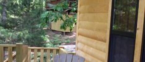 Een houten chalet met twee witte kunststof Adirondack stoelen op een houten terras.