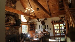 A rustic interior with a stone fireplace, wooden beams, and deer antlers mounted on the walls. - Bear Creek Lodge Cabin Resort (Walnut Shade)