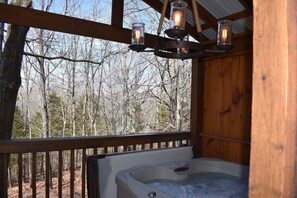 Un jacuzzi con terraza de madera y vistas a un bosque.
