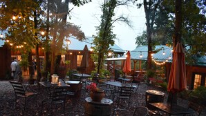 An outdoor patio area with tables and chairs, surrounded by trees and string lights. - Bear Creek Lodge Cabin Resort (Walnut Shade)